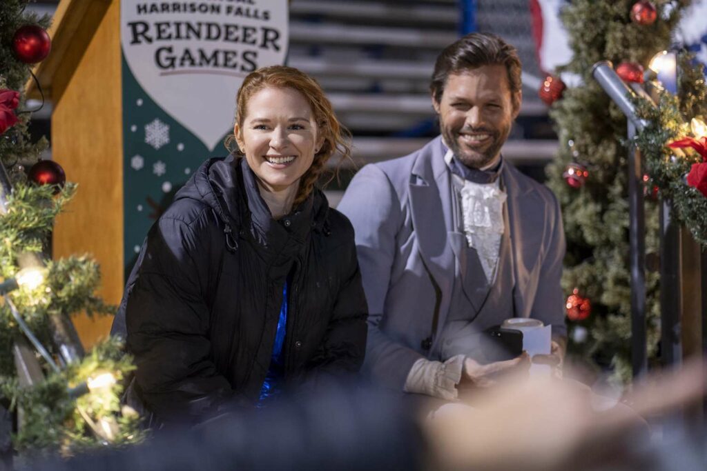 Sarah Drew y Justin Bruening sonriendo, en una escena de la película Tradición navideña