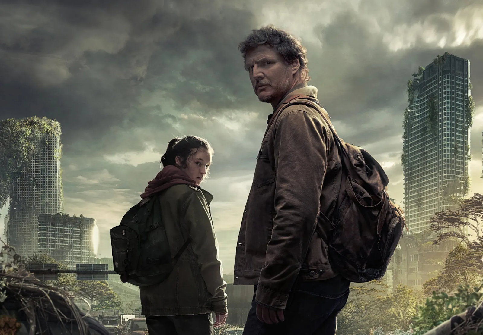 Joe (Pedro Pascal) y Ellie (Bella Ramsey) interpretando sus papeles en la serie The Last of Us. Llevan mochilas a sus espaldas la ropa ajada. De fondo se puede ver una ciudad destruida.