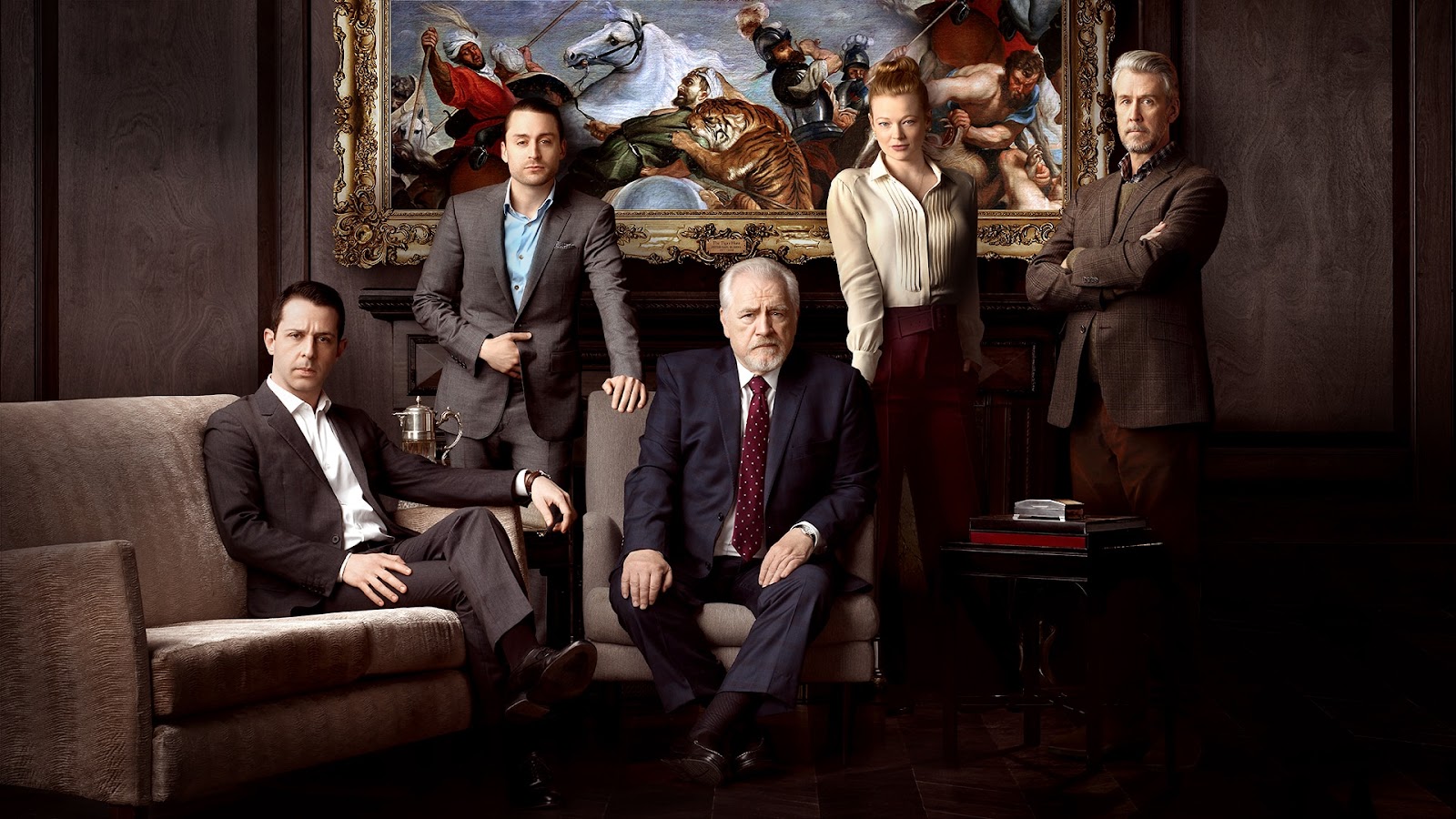 Plano general del cast de Succession, interpretando sus personajes. Al centro se encuentra Logan Roy, rodeado de sus cuatro hijos. Todos visten de traje formal.