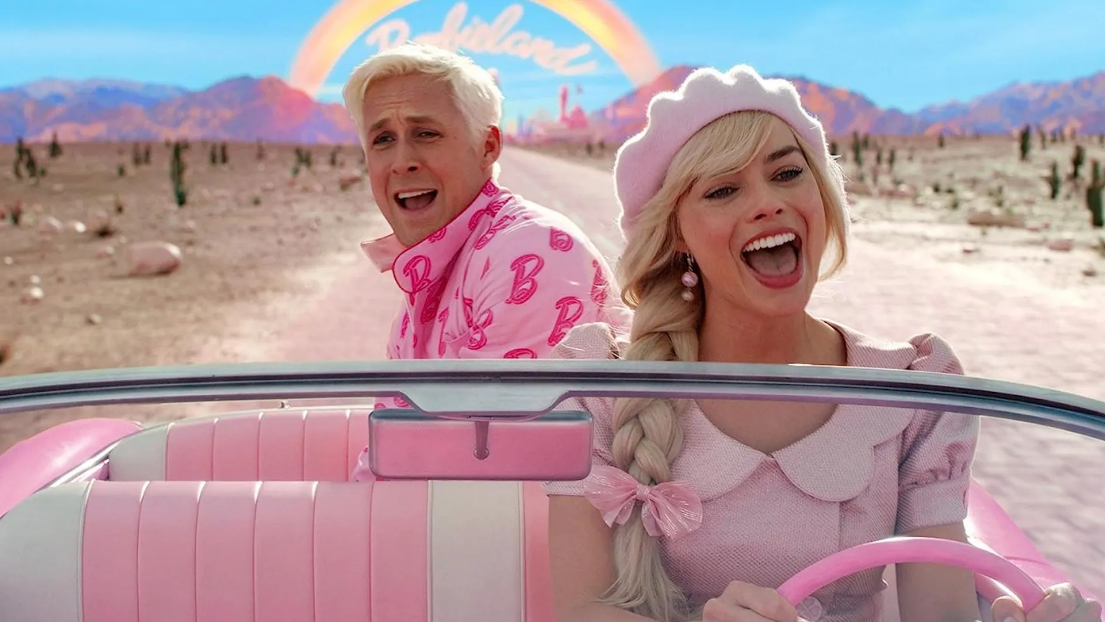 Margot Robbie y Ryan Gosling interpretando tus papeles en la película Barbie. Barbie maneja un descapotable rosado y lleva su cabello recogido en una trenza con una boina rosada y un lazo a juego. En el asiento de atrás se ve a Ken asomarse con una mueca de preocupación.