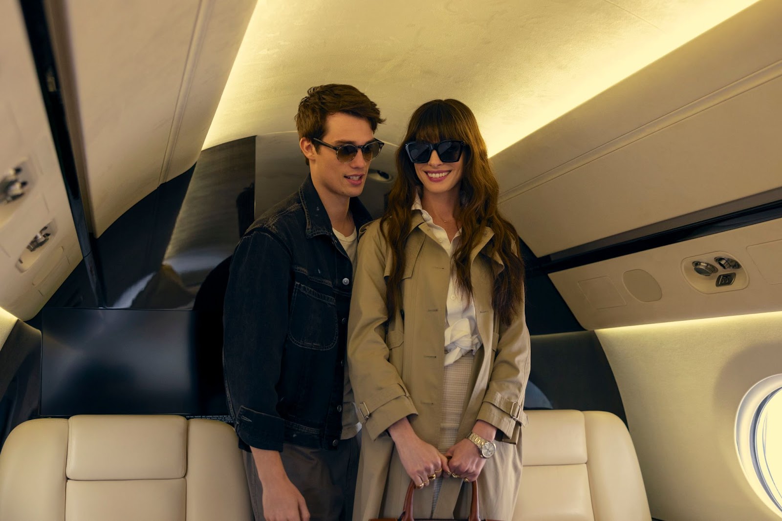 Los personajes de Anne Hathaway y Nicholas Galitzine, utilizando lentes de sol dentro de un avión privado en La idea de ti